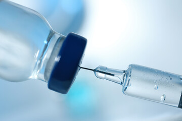 Filling syringe with COVID-19 vaccine on blurred background, closeup