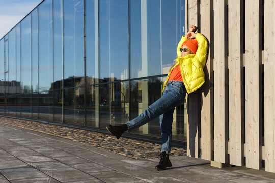 Stylish girl wearing yellow puffer and orange knitted hat