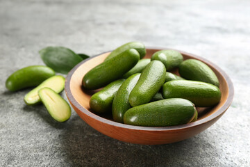Fresh seedless avocados in wooden bowl on grey table, closeup