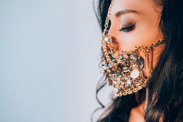 Ethnic beauty. Covid-19 fashion look. Festive party. Elegant woman in designer golden crystal chain face mask isolated on neutral side view copy space. - Powered by Adobe