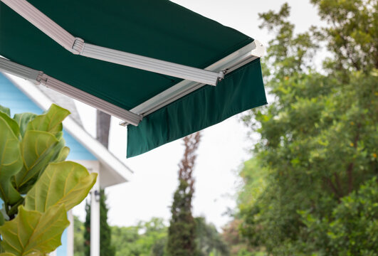 green awning of shop with garden background. exterior canvas roof.