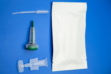Kit for home test for antibodies to coronavirus covid 19 on a blue background. The kit consists of an injection, a needle, a wet wipe, a solution and a pipette.