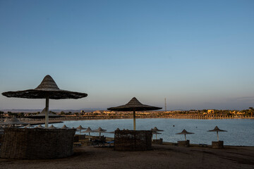 deserted beach with wicker umbrellas and lack of vacationers against the blue sky