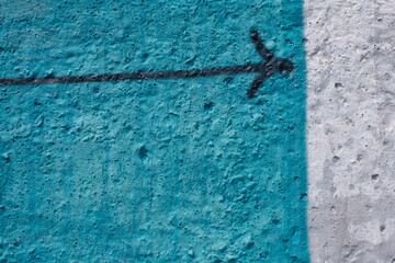 Directional arrow on a blue concrete wall background.