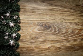 Wooden background with fir branches and silver stars.