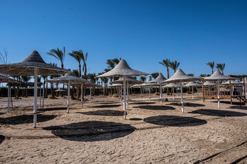 deserted beach with wicker umbrellas and lack of vacationers against the blue sky