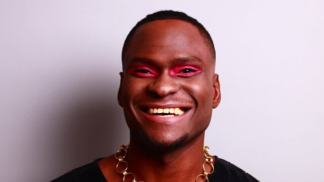 afro american man in dress style with pink eyeshadow and lipstick crossdressing in fashion show studio background