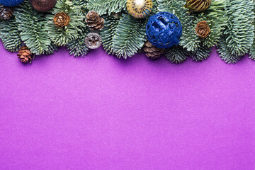 Purple Christmas background. Spruce twigs with New Year's toys, cones.