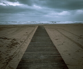 Wooden walkway on the beach on a rainy winter day.