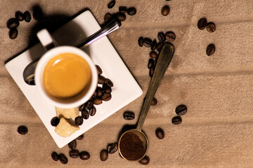 Rzut z góry na filiżankę espresso, ziarna brazylijsko-etiopskiej kawy oraz klasyczna łyżeczka z mieloną kawą