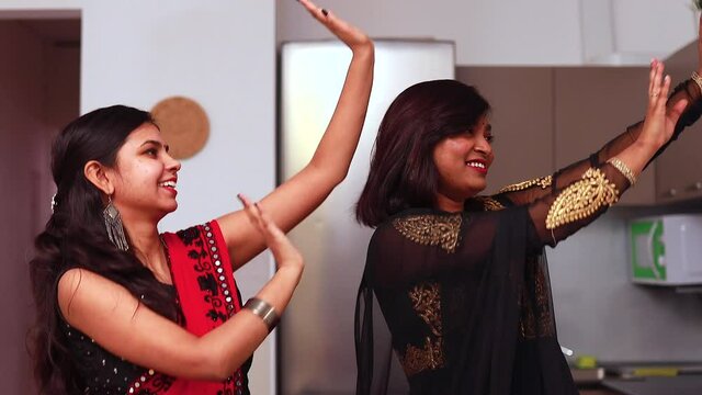 two beautiful indian happy sisters dancing in living room in home
