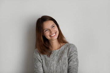 Obraz premium Happy millennial Caucasian woman isolated on grey studio background look in distance planning or dreaming. Happy young red-haired female feel overjoyed inspired daydream or visualize at home.