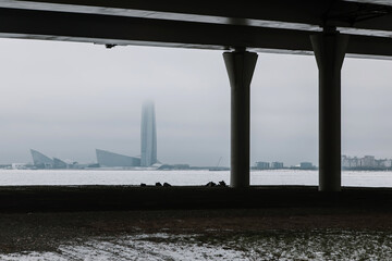 Columns under the flyover and a tall skyscraper in the distance. Conceptual architecture. Snowy winter day.
