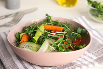 Salad with fresh organic microgreen in bowl on white table, closeup