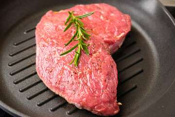 Raw fresh beef steak with a rosemary on a grill pan.