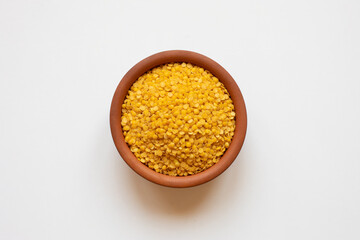 Dry yellow lentils in ceramic bowl. Isolated top view.