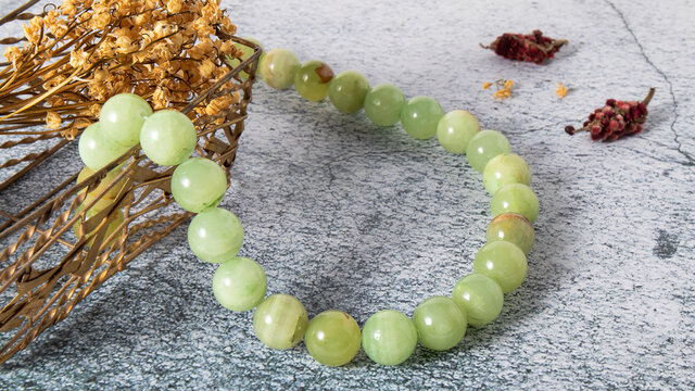 Luxurious natural bright onyx (agate) beads on a gray plastered surface. Retro composition of magical mineral and dried flowers.