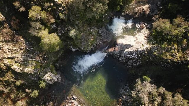 Aerial view of a mountain stream cascading into a clear pool at Pirio in Corsica