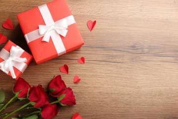 Gift boxes, roses and paper hearts on wooden background, flat lay with space for text. Valentine's...