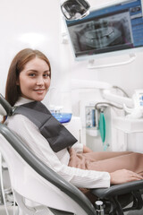 Fototapeta premium Vertical shot of a charming female patient smiling to the camera waiting for dental appointment at the clinic