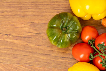 Brown wooden background with green tomato, red cherry tomatoes and peppers