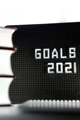 2021 Goals phrase on black background with blurred books and notebook concept for stating goals, strategy, ideas 
