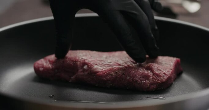 Slow motion man put beef steak pieces on nonstick pan