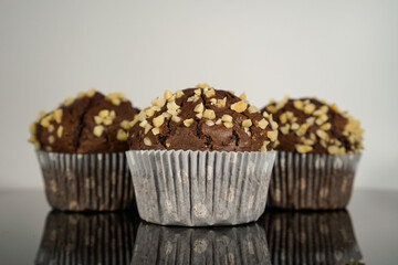 three chocolate muffins in front of a white background
