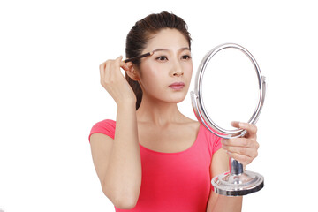 Young woman in pink dress holding a mirror,applying make-up