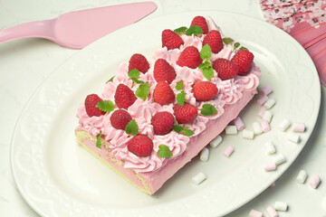 Raspberry Swiss roll with  marshmallows on white plate copy space