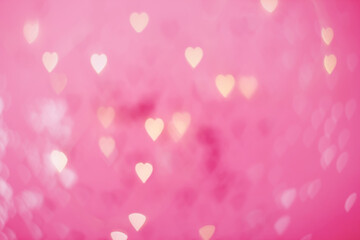 Yellow and pink bokeh in the shape of hearts on a pink background copy space. Valentine background