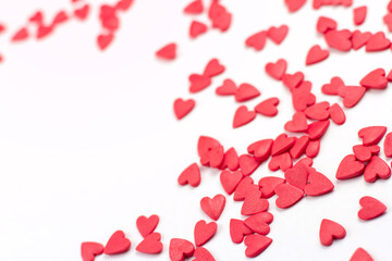 Red confectionery confetti in the shape of hearts on a white background copy space.