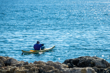 Man fishing in a pirogue in the sea with fishing rod