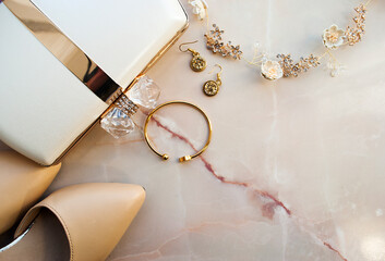 Women's handbag, shoes and jewelry on a light marble background. Top view. Place for text.