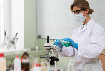 Scientist pouring substance from into Erlenmeyer flask in a laboratory during research