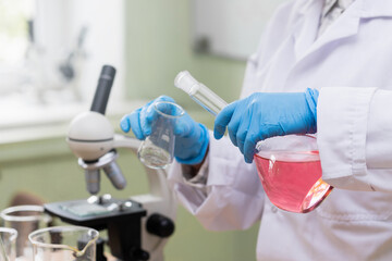Scientist pouring pink substance from one flask to another in a laboratory