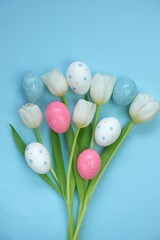 Easter holiday. White tulips flowers, pink and spotted Easter eggs on a light blue background.. Easter colorful eggs in pastel colors set.Spring festive 
 background.Easter symbol.