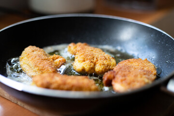 Fried pieces of breaded chicken. Preparation of a traditional dinner.
