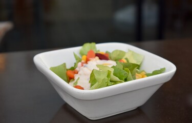 A bowl of salad with dressing on a restaurant table