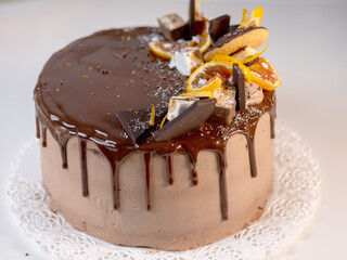 beautiful chocolate cake with oranges, drizzled with chocolate icing on a light table