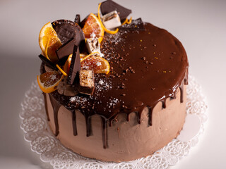 beautiful chocolate cake with oranges, drizzled with chocolate icing on a light table
