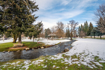 Fototapeta na wymiar A small creek runs through the small public park with snow during winter at Rathdrum, Idaho USA.