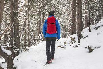 A man in the snow with a red backpack