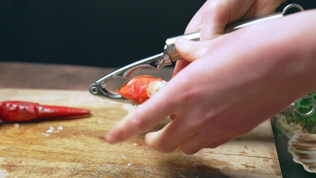 Close-up of cracking cooked red lobster with seafood tool and Lobster Cracker. Concept of eating luxury food with special tools in 4K. Cracking lobster claws with a nutcracker in slow-motion.
