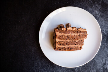 piece of chocolate cake with cream on a white plate ready to eat on the table for healthy meal snack outdoor top view copy space for text food background rustic image