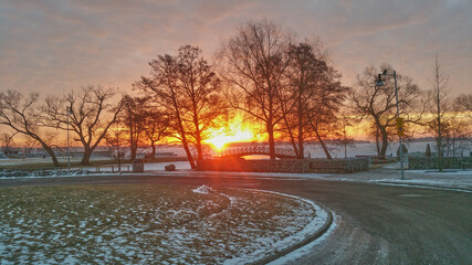 Fototapeta premium Sunrise in a cold winter morning with a view of icy lake bridge and trees