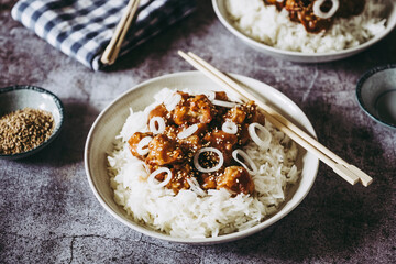 Choux-fleur caramélisé aux graines de sésame et petits oignons accompagné de riz blanc dans une assiette - Plat gourmand asiatique