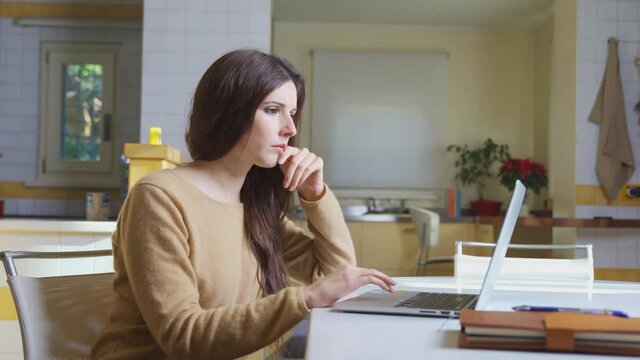 Frustrated businesswoman worker upset working from home on computer laptop, cute woman sitting in modern interior kitchen table with agenda. Businesswoman Smart working icon