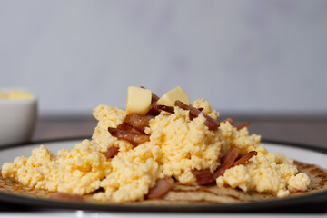 Scrambled eggs and bacon on Derbyshire oatcakes side view