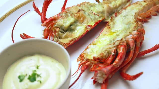Close-up of grilled red lobster with sauces, butter and spices in serving plate. Concept of freshly made luxury seafood with tropical fruits and sauce on the side, a restaurant-style in 4K.
